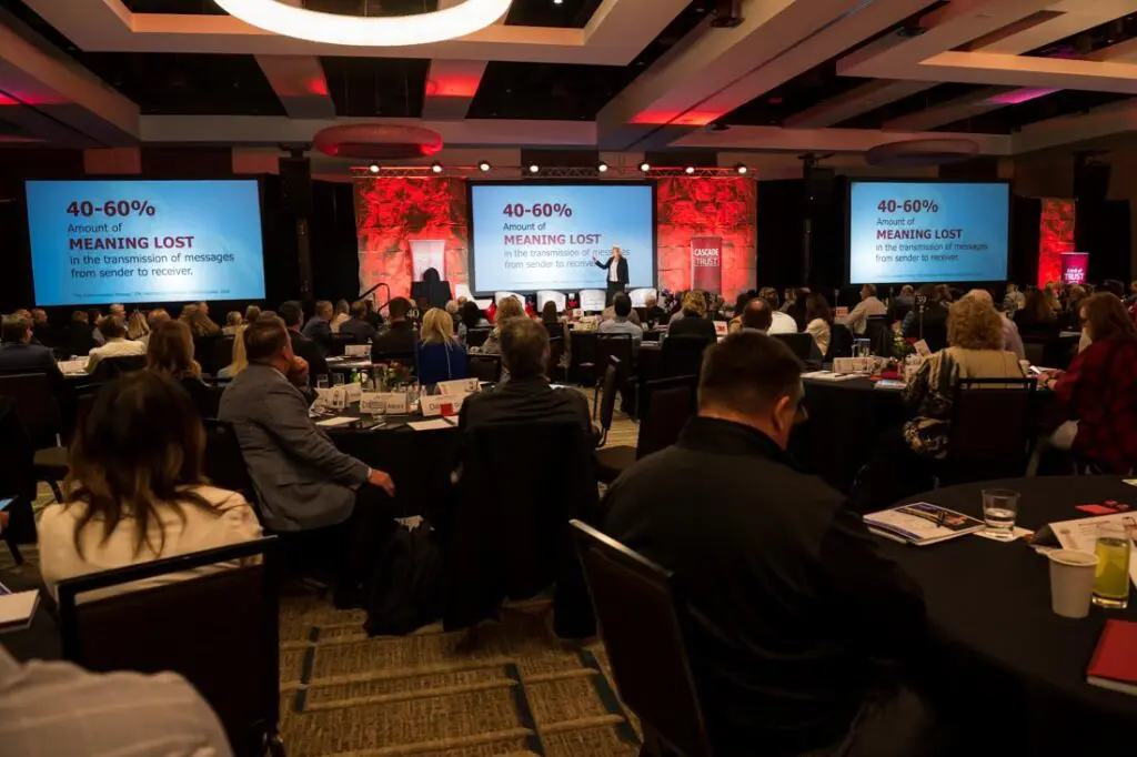 Conference attendees watching a presentation on stage.