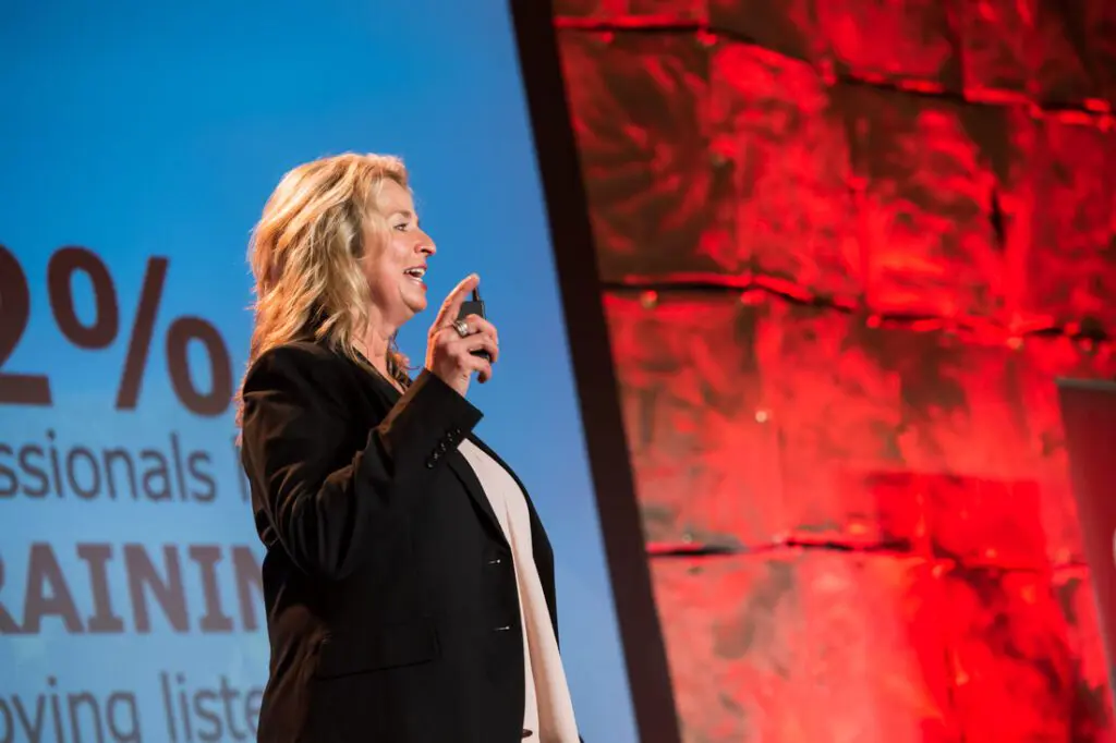 Woman speaking at a conference stage.