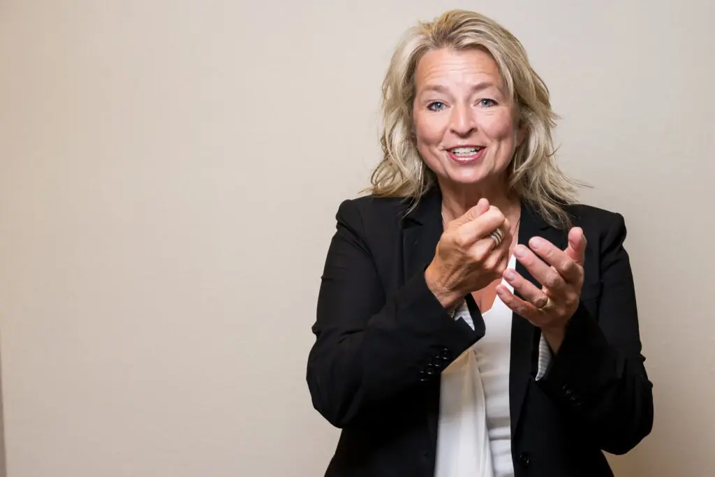 Smiling woman gesturing in business attire.