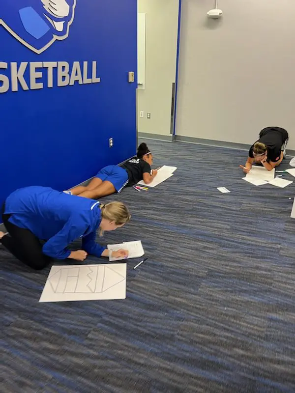 People drawing on floor in hallway.