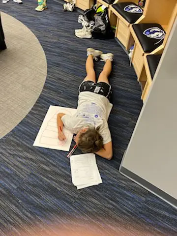 Person lying on floor doing homework.