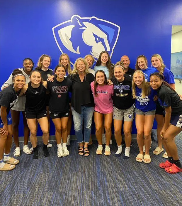 Group of people smiling in front of logo.