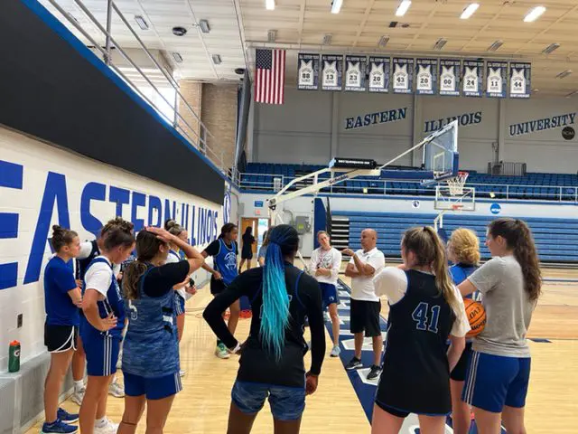 Basketball team huddle in university gymnasium.