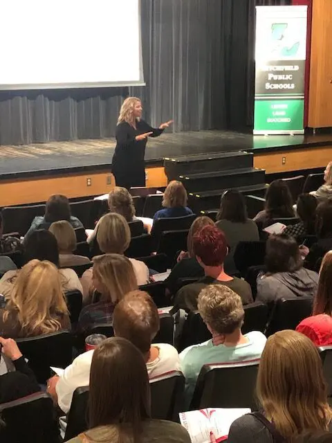 Speaker addressing audience in school auditorium.