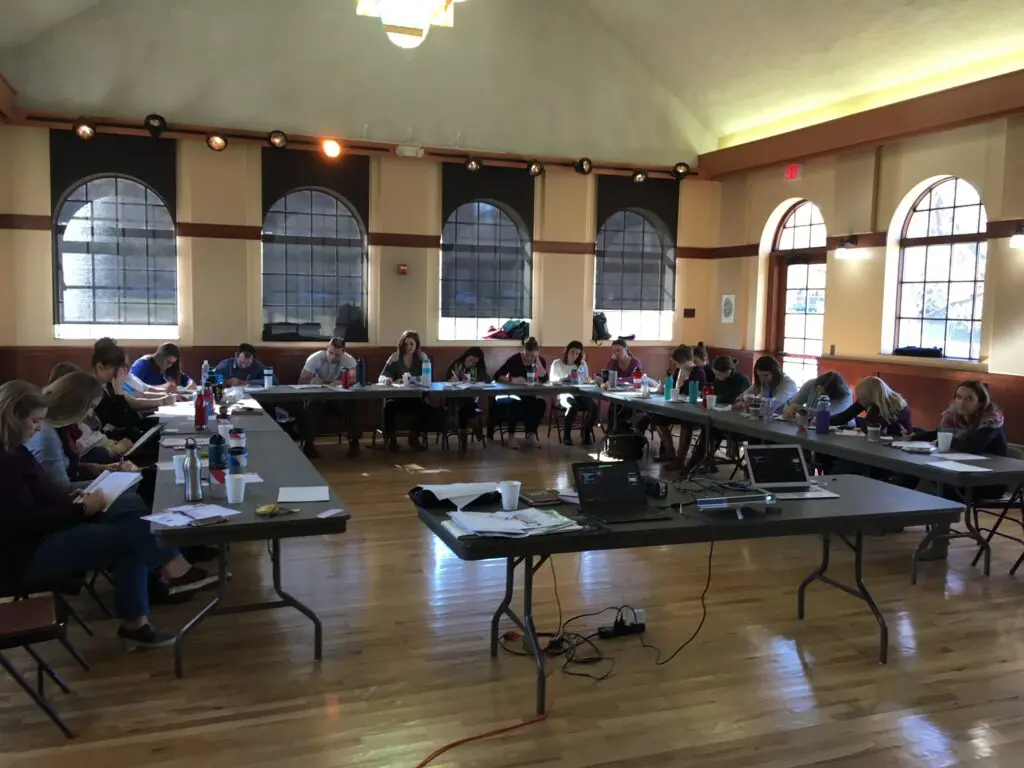 People seated around tables in a meeting.
