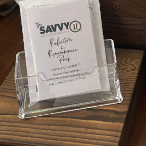 A business card holder with a Savvy Real Estate card on a wooden surface.