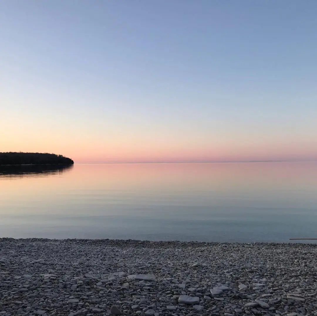 Calm sunrise over a rocky lakeshore.