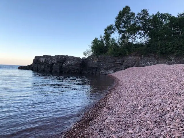 Rocky shoreline with trees and calm water.