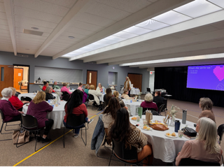 People attending a conference in a large room with a presentation.