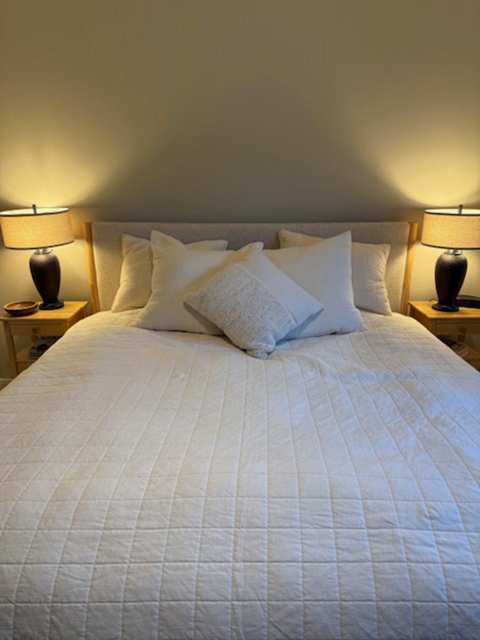 Cozy bed with white linens and two bedside lamps.