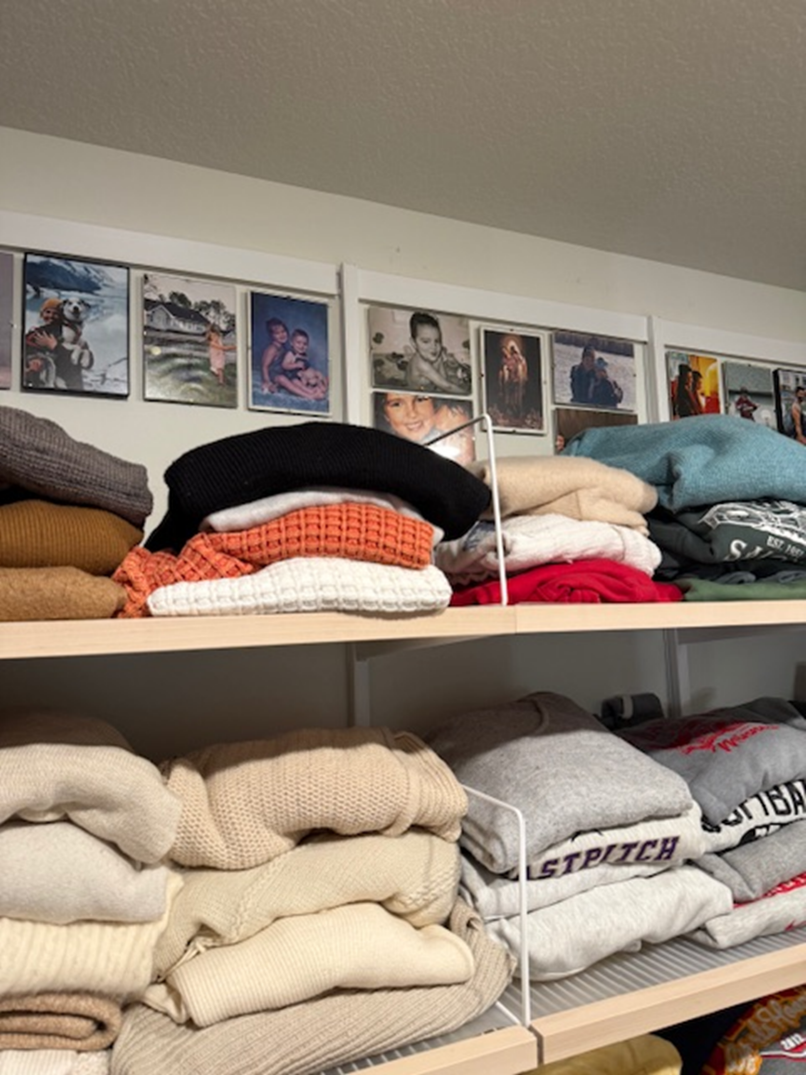Neatly folded sweaters and clothes on white shelves in a cozy room.