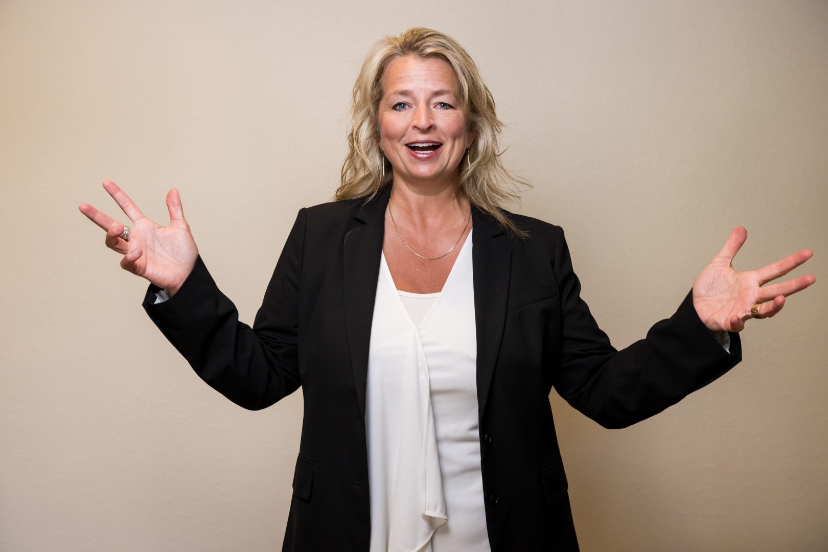 A woman in black jacket and white shirt holding her hands up.