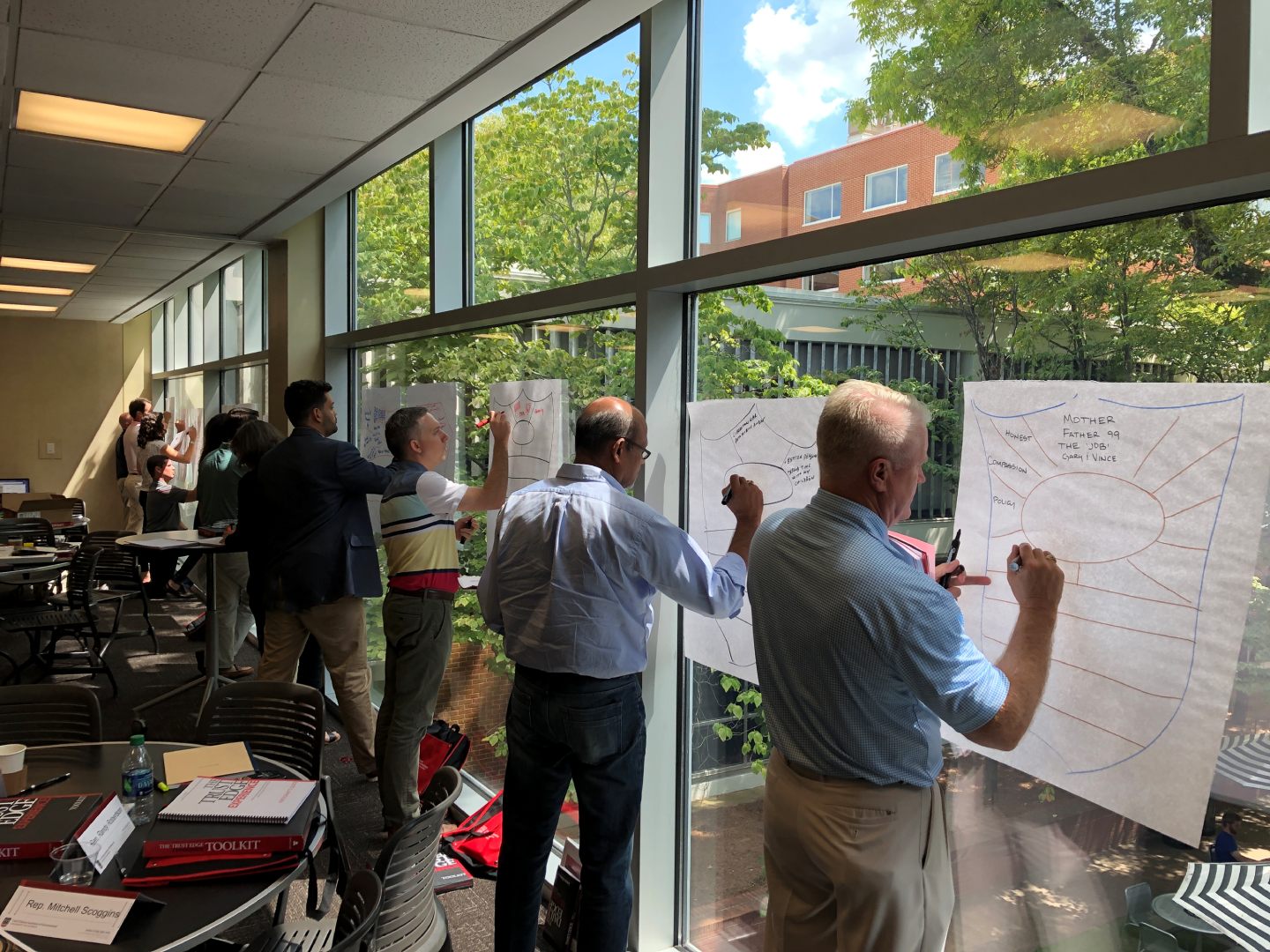 A group of people standing in front of windows writing on paper. A group of people standing in front of windows writing on paper.
