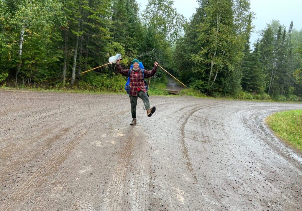 Person joyfully hiking on a dirt road.